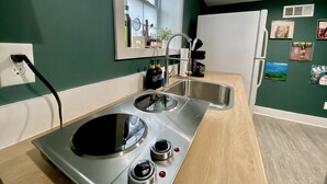 Een compacte keuken met een inbouwfornuis, een spoelbak en een koelkast.