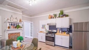 A modern kitchen with white cabinets, a stainless steel refrigerator, and a dining area with a glass table and chairs. - Lumiére of Marietta Square (Marietta)
