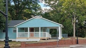Een gelijkvloers huis met een veranda, een fundering van baksteen en een lantaarn in de buurt.