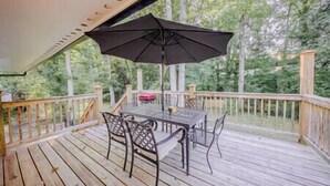 A wooden deck with a table and chairs, an umbrella, and a railing. - The Grand Slam - The Battery ATL (Smyrna)
