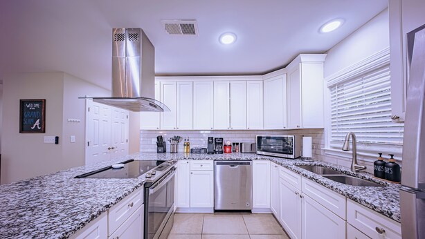 A modern kitchen with white cabinets, stainless steel appliances, and granite countertops. - The Grand Slam - The Battery ATL (Smyrna)