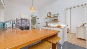 Una cocina moderna con una isla de madera, armarios blancos y un salpicadero colorido.