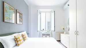 A bedroom with a bed, pillows, a dresser, a nightstand, a window, and two framed pictures on the wall. - Bilocale in zona Isola - Garibaldi (Milan)