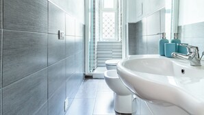 A modern bathroom with grey tiles, a white sink, and a shower. - Bilocale in zona Isola - Garibaldi (Milan)
