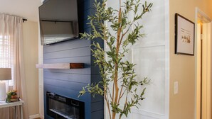 A modern living room with a built-in fireplace, a large window with curtains, and a potted plant. - Mountain Retreat 4 Miles to Park Entrance Walk to Dining (Three Rivers)