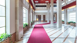 A spacious hallway with a red carpet, large windows, and columns. - [Vista Duomo] Trilocale vintage vicino a Centrale (Milan)
