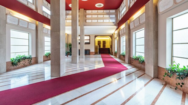 A spacious lobby with a red carpet, large columns, and potted plants. - [Vista Duomo] Trilocale vintage vicino a Centrale (Milan)