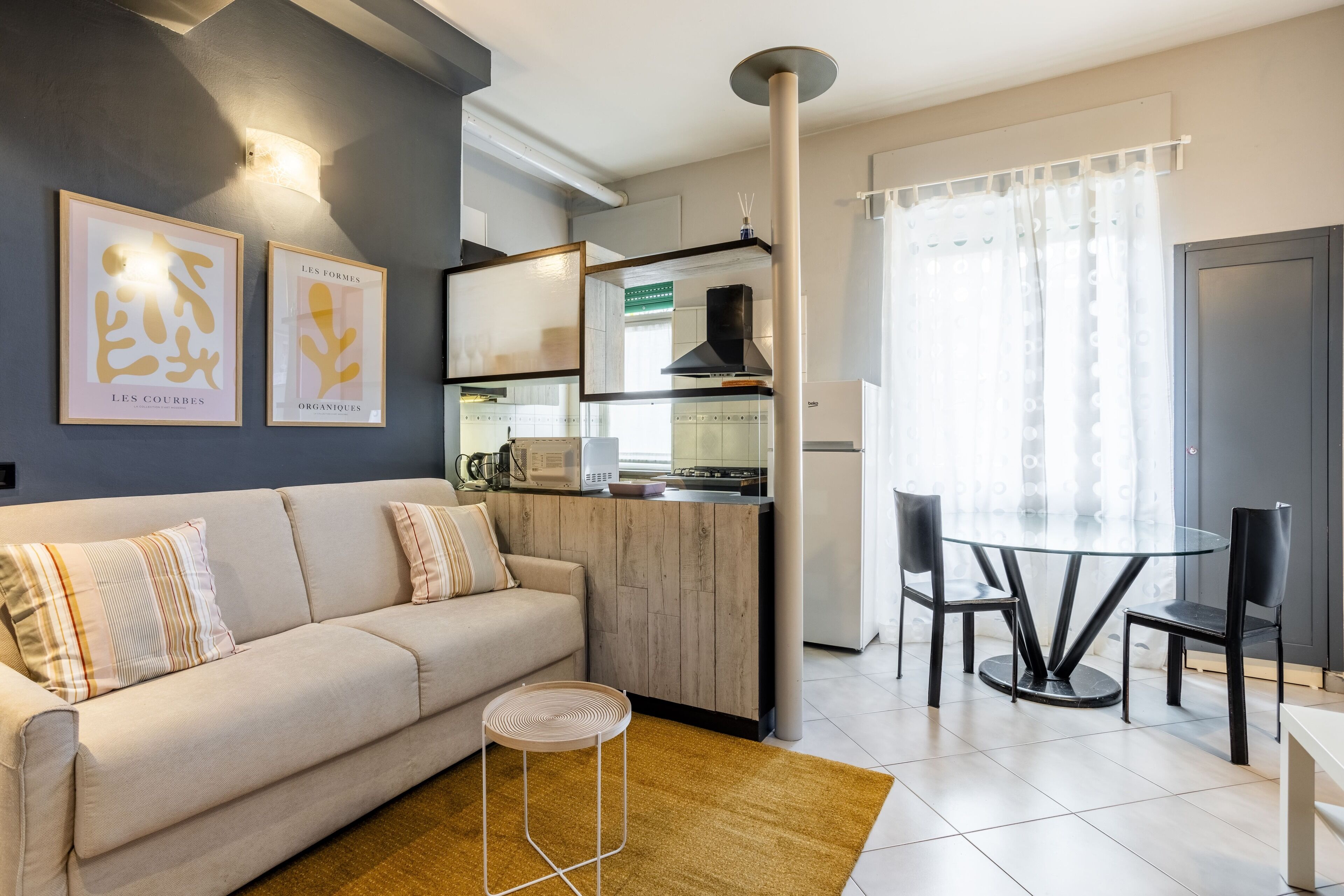 Een moderne woonkamer met een bank, een salontafel en een eethoek met een ronde tafel en stoelen.