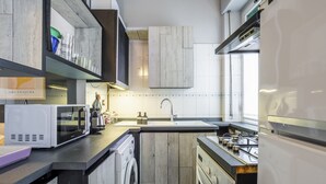 Een praktische keuken met een wasmachine, magnetron, spoelbak en fornuis.