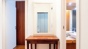 A hallway with a wooden door, a mirror on a wooden table, and a bathroom with a sink and mirror. - [Niguarda] Bright and comfortable Flat (Milan)