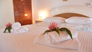 A neatly made bed with rolled white towels and pink flowers, a wooden door, and a nightstand with a lamp. - Villa Eleni Peritheia by Corfu Escapes (Corfu)