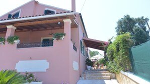 A pink building with a balcony, steps leading to the entrance, and potted plants. - Villa Eleni Peritheia by Corfu Escapes (Corfu)
