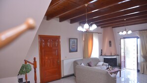 A living room with a wooden staircase, a fireplace, and a sofa. - Villa Eleni Peritheia by Corfu Escapes (Corfu)