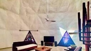 A tent-like interior with a flat-screen TV, a wooden table, and a sofa.