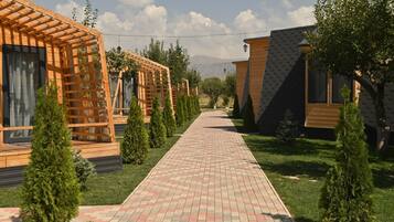 A pathway leading to wooden cabins with a clear sky and mountains in the background.
