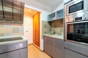 A modern kitchen with stainless steel appliances, a wooden door, and a tiled backsplash. - Malhara Apartment (Sevilla)