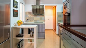 A modern kitchen with a central island, stainless steel appliances, and a variety of wall decorations. - Malhara Apartment (Sevilla)