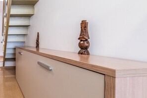 A modern interior with a staircase, a wooden cabinet with a drawer, and a decorative wooden piece on the wall. - Malhara Apartment (Sevilla)