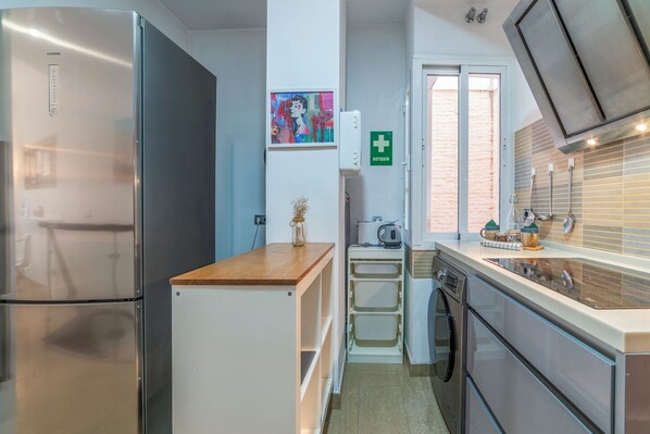 A compact kitchen with a refrigerator, dishwasher, and a small sink area. - Malhara Apartment (Sevilla)