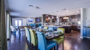 A spacious kitchen with dark wood cabinets, a central island, and modern lighting fixtures. - The Oasis, a Vegas Villa (Las Vegas)