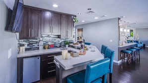 A modern kitchen with dark wood cabinets, a tiled backsplash, and a central island with bar stools. - The Oasis, a Vegas Villa (Las Vegas)