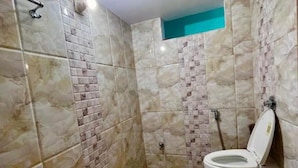 A bathroom with a toilet, shower, and tiled walls. - 100m from Ganges River & Dasashwamedh Ghat, 1-bedroom  in Varanasi with AC, WiFi (Varanasi)
