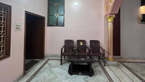 A room with a marble floor, a black coffee table, and four wooden chairs. - 100m from Ganges River & Dasashwamedh Ghat, 1-bedroom  in Varanasi with AC, WiFi (Varanasi)