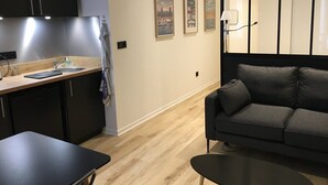A modern kitchen with a sink, countertop, and cabinets. There is a dining table and a sofa in the living area. - Superb studio with balcony city center Opera (Lyon)