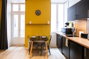 Une cuisine moderne avec une table à manger, des chaises, une horloge et un four à micro-ondes.