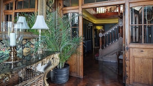 Un amplio pasillo con paneles de madera, una escalera y una planta en maceta.