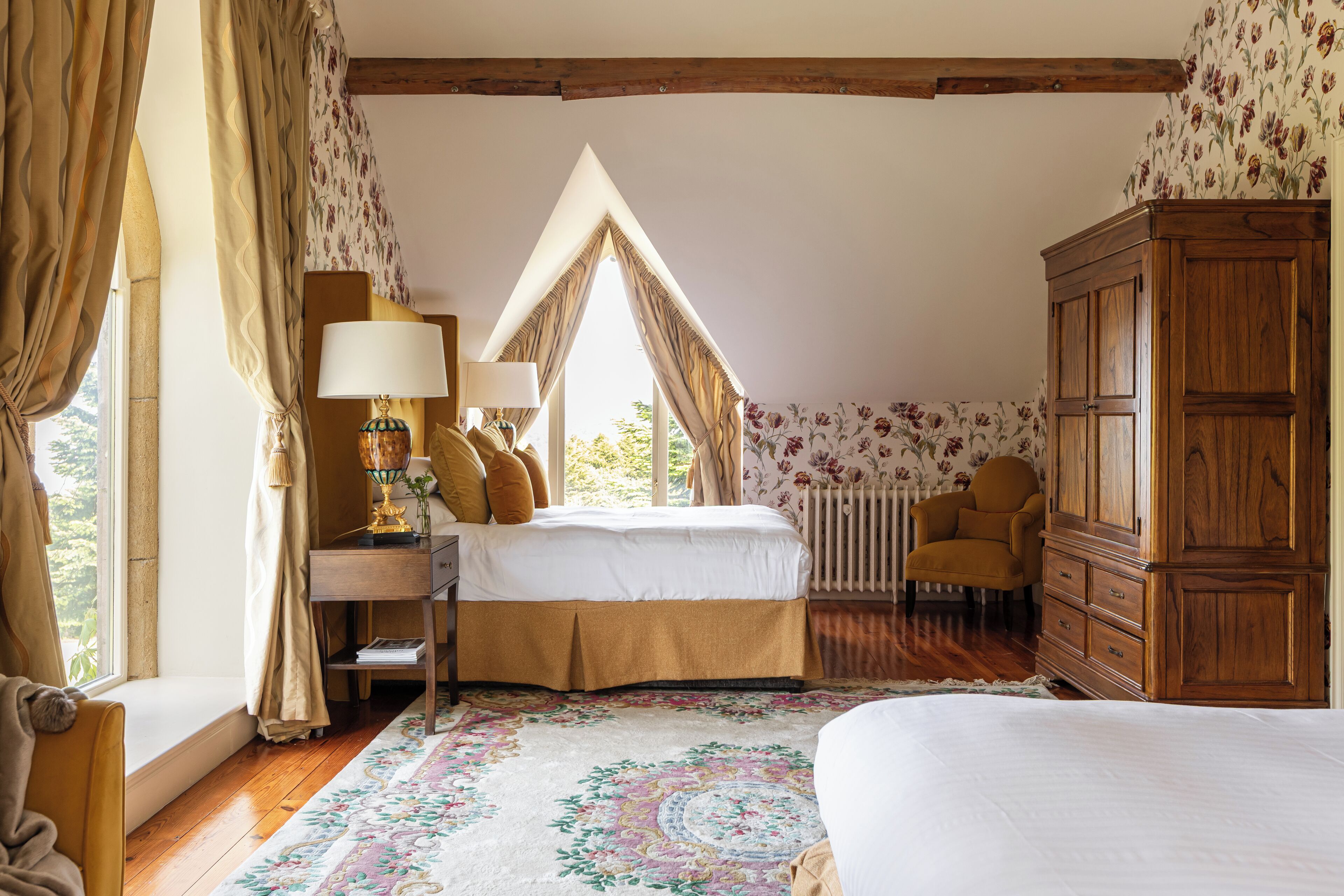 A bedroom with a bed, a desk, a chair, a wardrobe, and a window with curtains.
