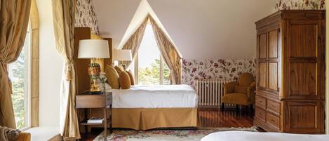A bedroom with a bed, a desk, a chair, a wardrobe, and a window with curtains.