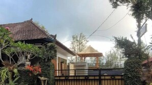 A gated residential property with a tiled roof, a small gazebo, and lush greenery. - Umah Yugadi Bali (Bali)