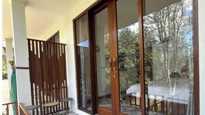 A balcony with a wooden railing, a small round table, and a chair. - Umah Yugadi Bali (Bali)