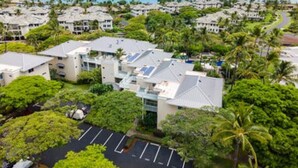 A resort with multiple buildings, a parking lot, and a view of the ocean.