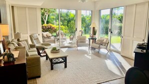 A spacious living room with a large sliding glass door leading to a patio, furnished with sofas, chairs, and a coffee table.