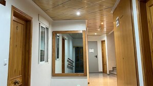Un corridoio con porte in legno, un grande specchio e un pavimento piastrellato.