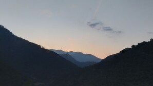 Eine gebirgige Landschaft mit einem Gebäude links und blauem Himmel.