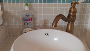Ein Badezimmerwaschbecken mit weißer Schüssel und Messingarmatur.
