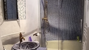 Ein kleines Badezimmer mit Waschbecken, Toilette und einer Duschkabine aus Glas.