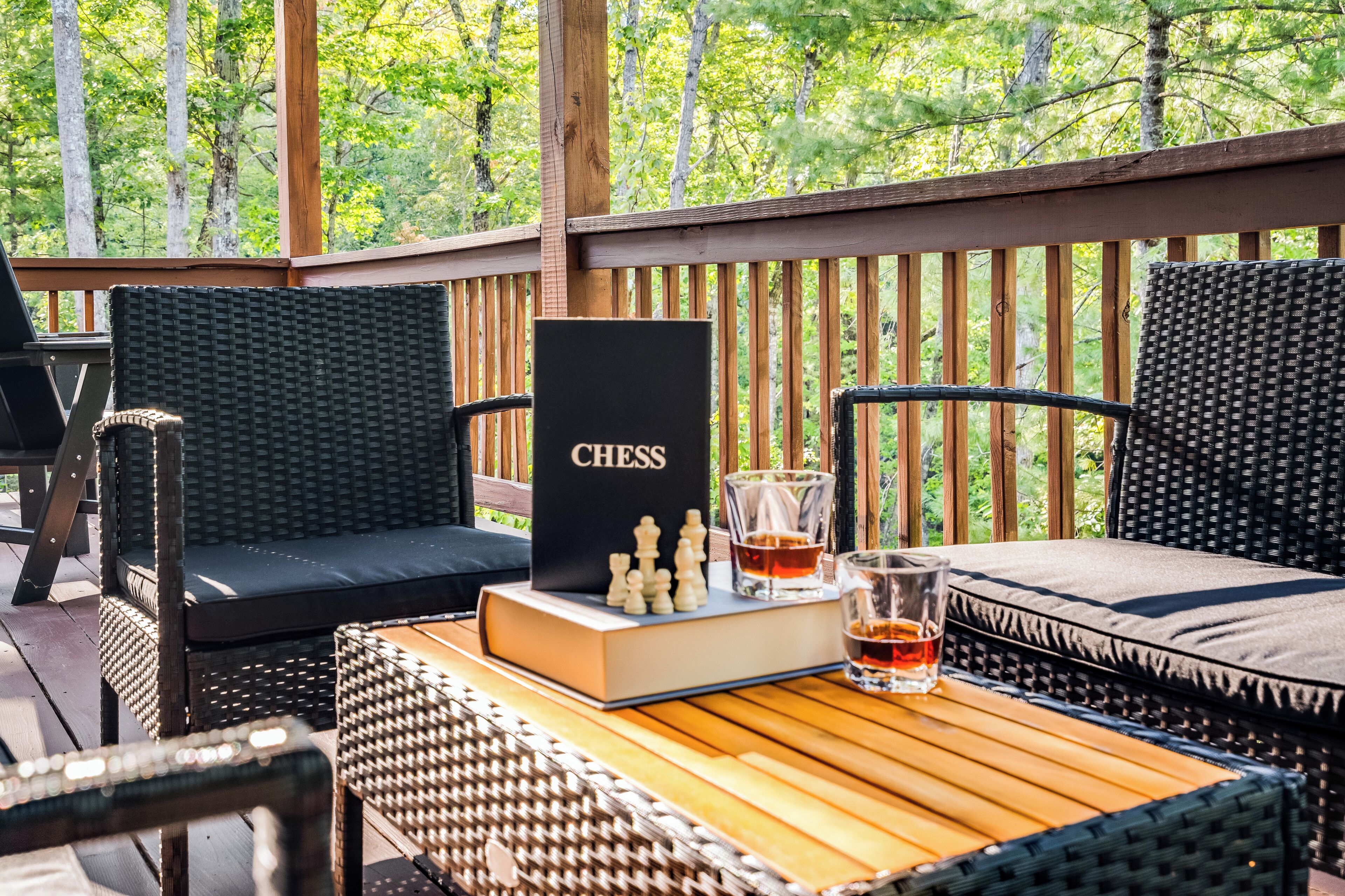 Une terrasse en bois, meublée de meubles en osier, avec un jeu d’échecs posé sur une table.
