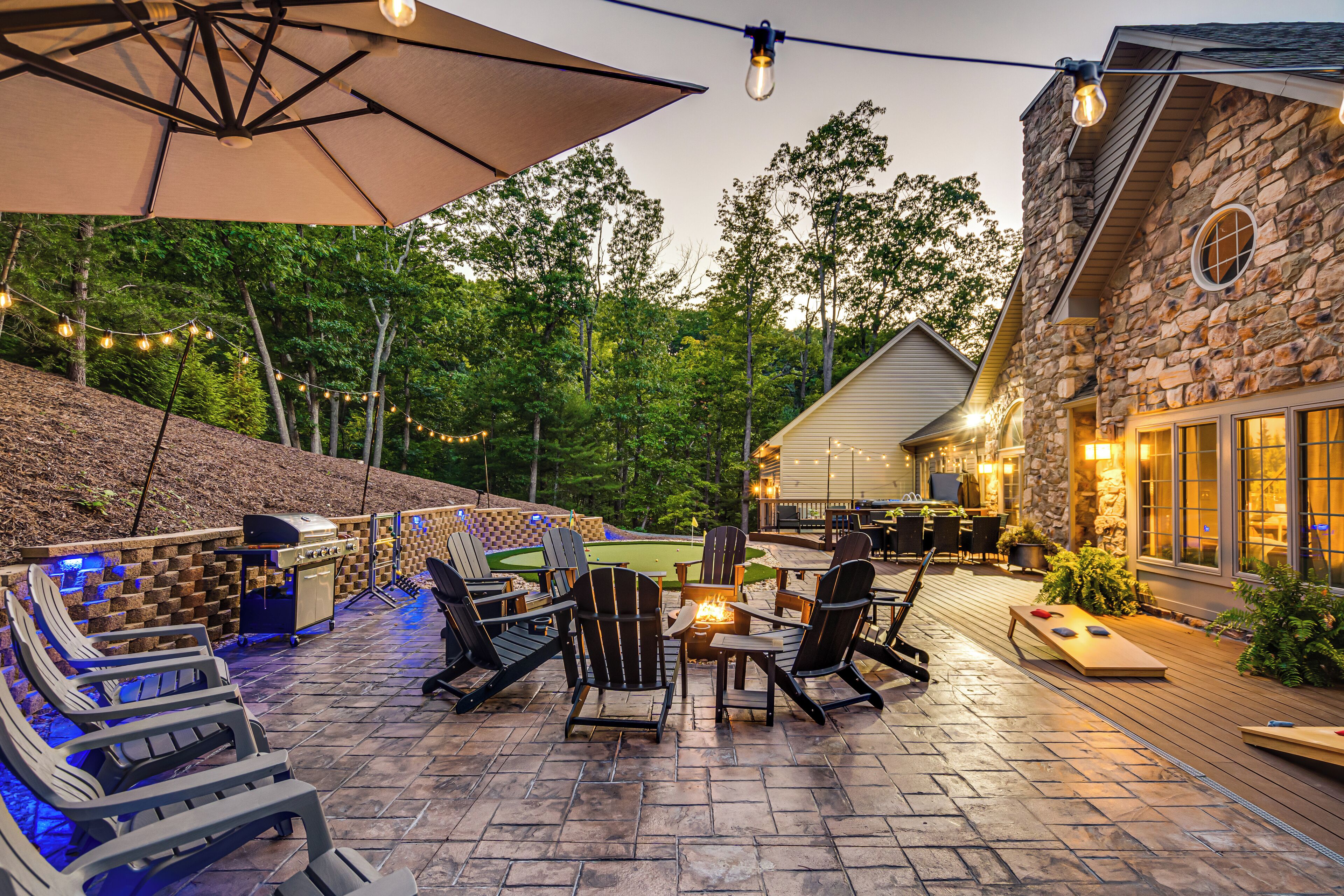 An outdoor patio with Adirondack chairs, a grill, and a fire pit.