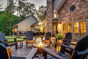 Una casa de piedra con un patio que tiene mobiliario exterior y una chimenea.