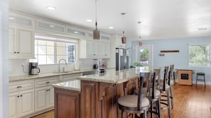 A kitchen with white cabinetry, a granite countertop, a stainless steel refrigerator, and a bar area with stools. - Wine Country Retreat Gorgeous Views, Minutes to Wineries (Temecula)