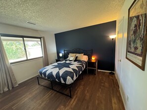 Un dormitorio con cama, dos lámparas de noche, una ventana y un cuadro en la pared.