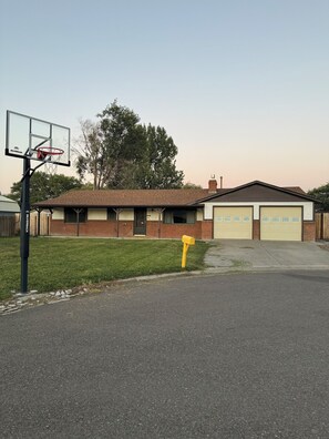 Un edificio residencial con garaje, canasta de baloncesto y buzón.