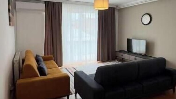 A living room with a sofa, a black couch, a TV, and a lamp.