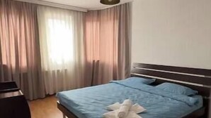 A bedroom with a bed, a desk, and a hanging light fixture.