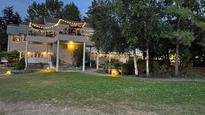 A two-story house with a balcony, surrounded by trees and a well-maintained lawn.