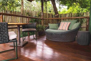 An outdoor patio area with wicker furniture, including a sofa and chairs, and a wooden table. - Casa da Lua Pousada (Alto Paraíso de Goiás)